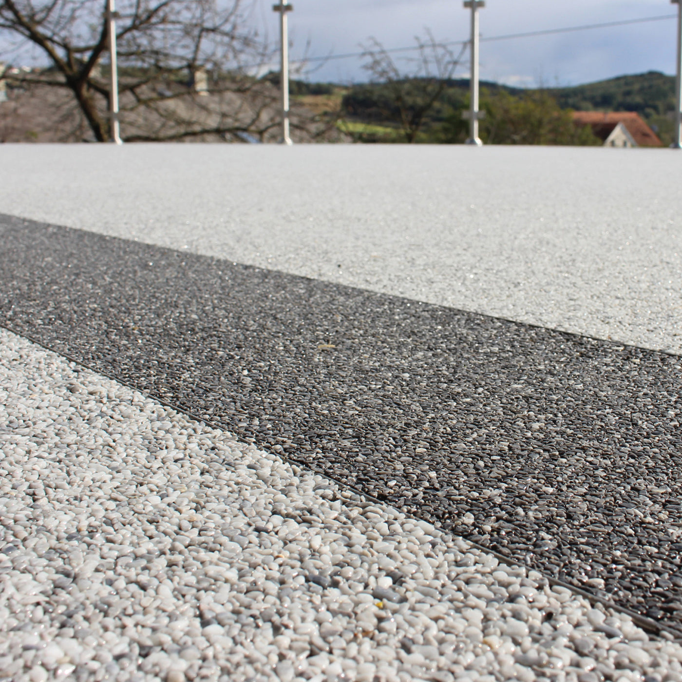 Straße mit grauem und weißem Kiesbelag, im Freien.