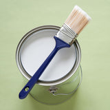 Pinsel auf Farbeimer, grünem Hintergrund.