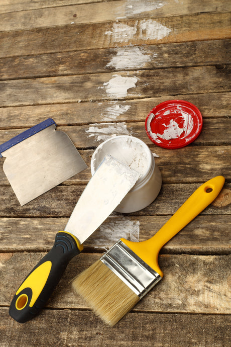 Pinsel, Spachtel, Farbe auf Holz.