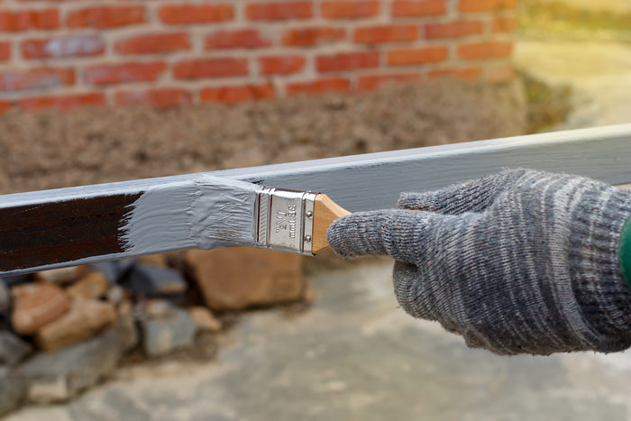 Pinsel streicht graue Farbe auf.