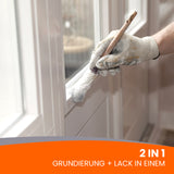 Pinsel streicht weißen Lack auf.